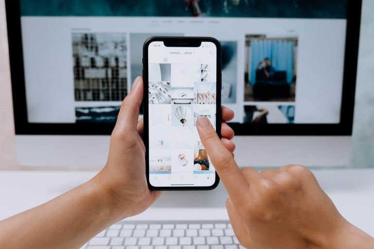 finger touching a cell phone screen with desktop in background