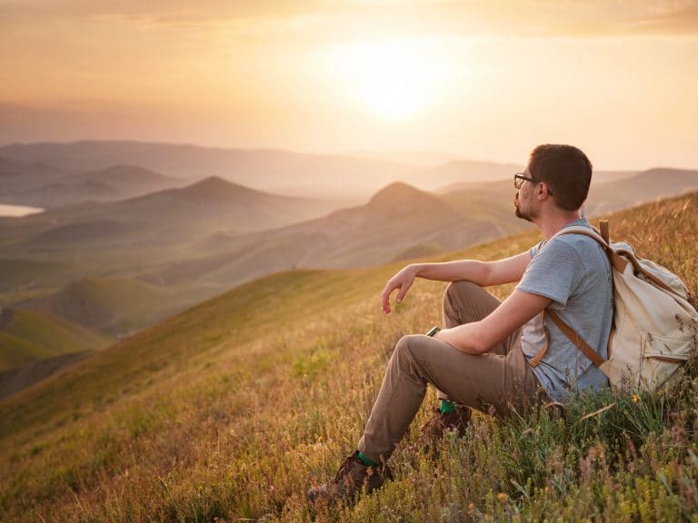 young man travels alone on the backdrop of the mountains