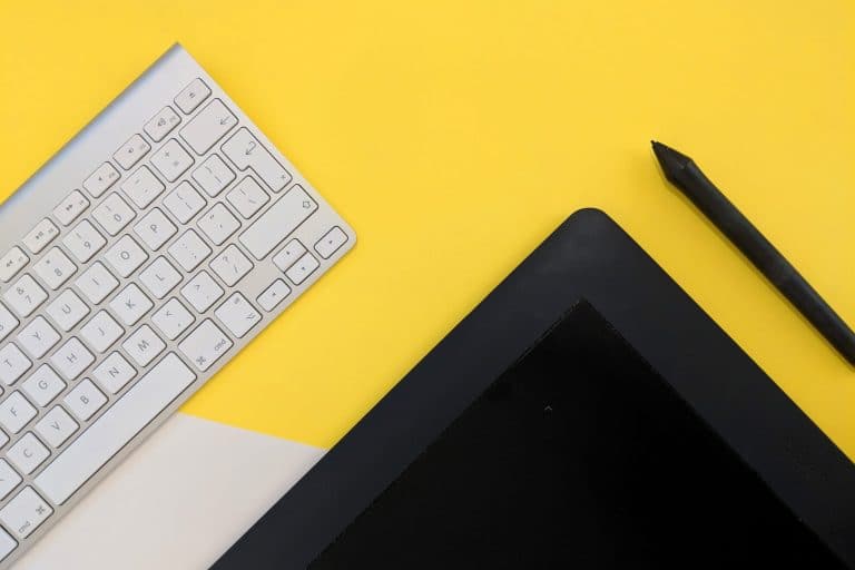 mac keyboard with black tablet on yellow background
