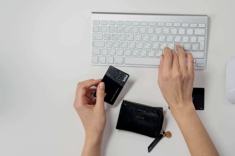 person holding a credit card near a computer keyboard