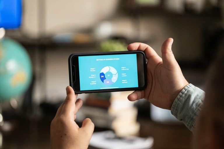 person holding cell phone landscape way and looking at a round graphic on the screen