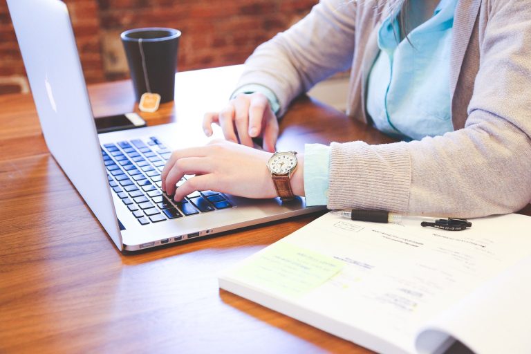 person sitting at a table typing on their laptop
